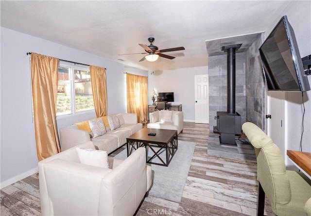 living room with hardwood / wood-style floors, ceiling fan, and a wood stove