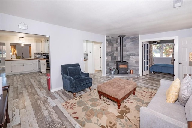 living room with a wood stove, sink, and light hardwood / wood-style flooring