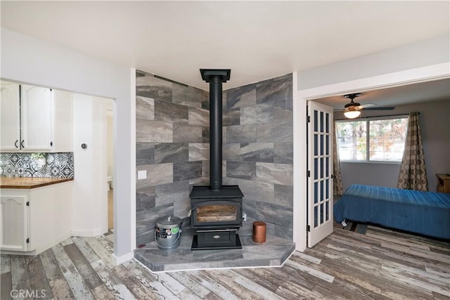 unfurnished living room featuring hardwood / wood-style flooring, tile walls, and ceiling fan