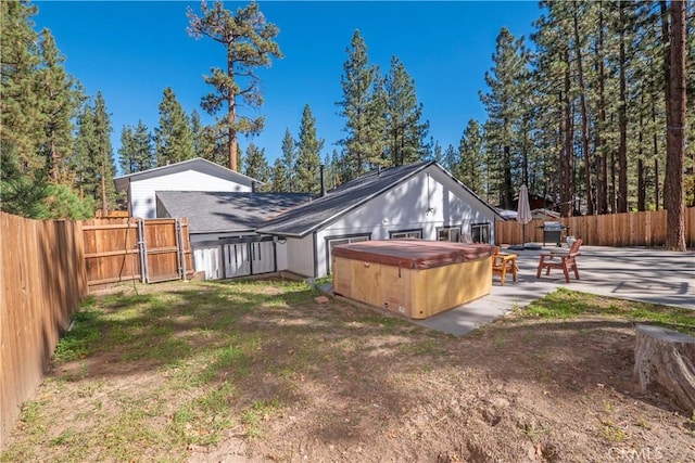 back of house featuring a yard, a patio, and a hot tub