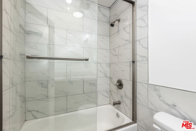 bathroom featuring tiled shower / bath combo and toilet