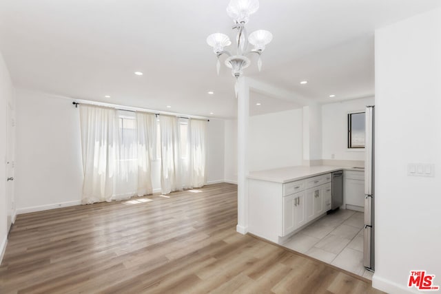 kitchen with hanging light fixtures, white cabinets, light hardwood / wood-style floors, and a notable chandelier