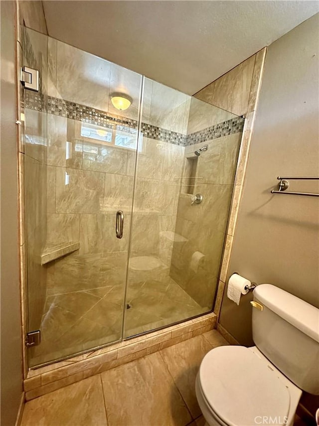 bathroom with toilet, tile patterned floors, and a shower with door