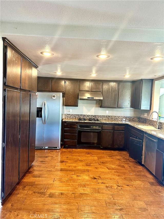 kitchen featuring sink, a textured ceiling, black appliances, and dark brown cabinets