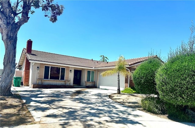 single story home with an attached garage, a tiled roof, driveway, board and batten siding, and a chimney