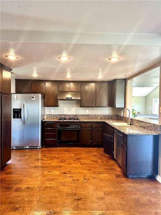 kitchen featuring sink, stainless steel fridge with ice dispenser, dark brown cabinets, and oven