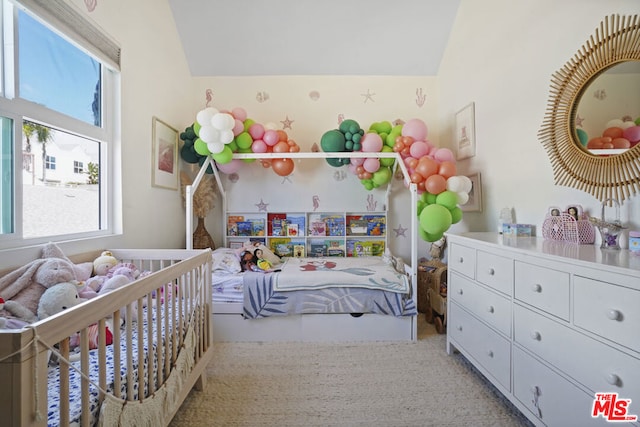 bedroom featuring carpet flooring, vaulted ceiling, and a nursery area