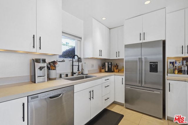 kitchen featuring white cabinetry, stainless steel appliances, light tile patterned flooring, and sink