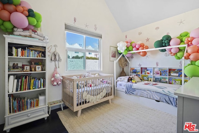 bedroom featuring a nursery area and high vaulted ceiling