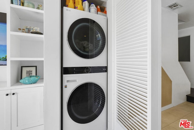 washroom with stacked washer / drying machine and light tile patterned floors