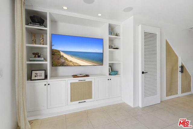 unfurnished living room with built in shelves and light tile patterned flooring