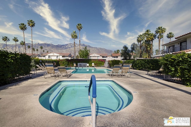 view of pool featuring a mountain view, a hot tub, and a patio