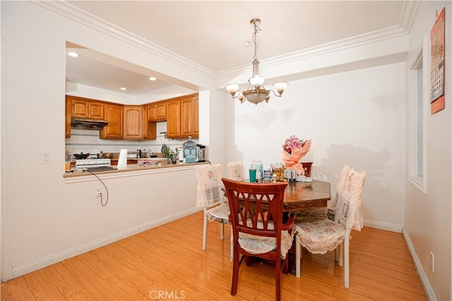 dining area featuring light wood-type flooring, crown molding, and an inviting chandelier