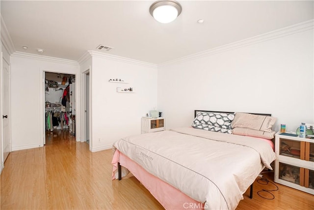 bedroom with a closet, ornamental molding, and hardwood / wood-style floors