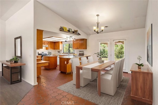 dining room featuring a healthy amount of sunlight, dark tile patterned flooring, lofted ceiling, and a chandelier