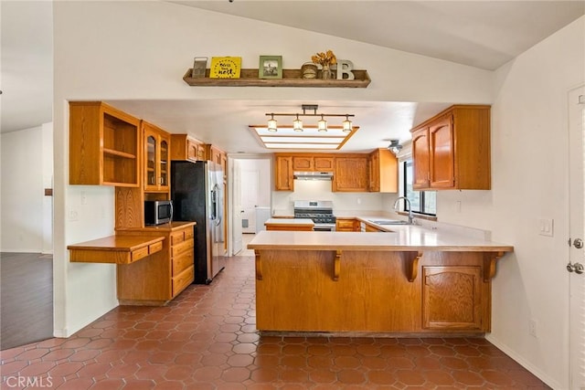 kitchen with stainless steel appliances, kitchen peninsula, a breakfast bar, sink, and lofted ceiling