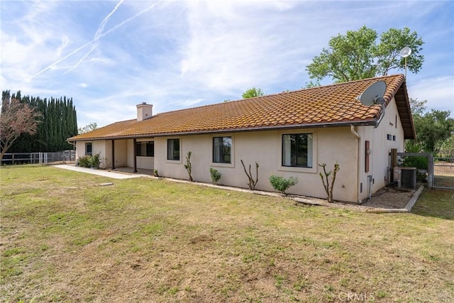 rear view of property featuring central AC and a lawn