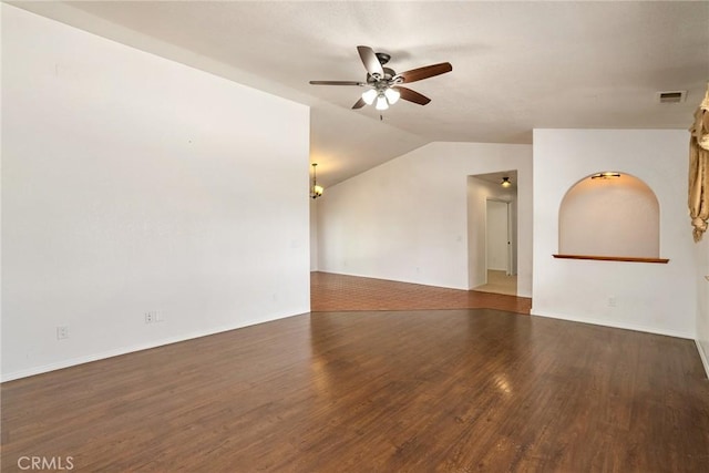 spare room featuring lofted ceiling, ceiling fan with notable chandelier, and dark wood-type flooring