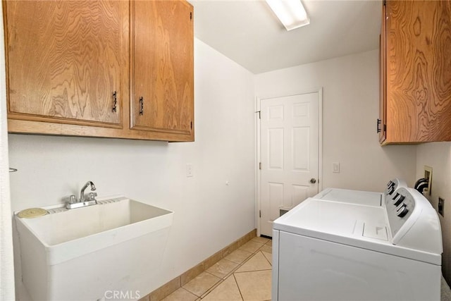 clothes washing area with sink, cabinets, washing machine and clothes dryer, and light tile patterned floors