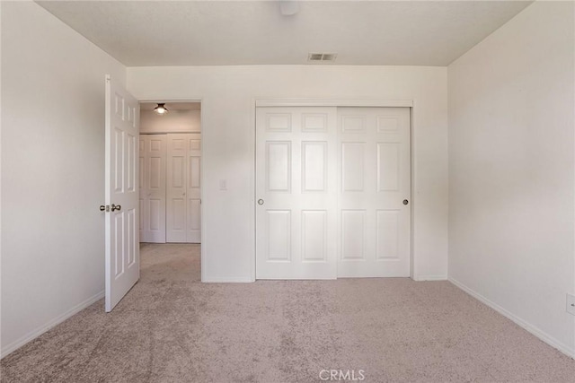 unfurnished bedroom featuring light colored carpet and a closet