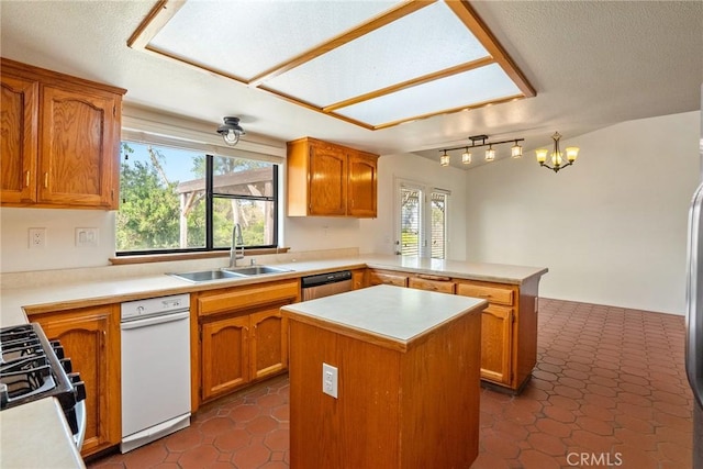 kitchen featuring kitchen peninsula, dark tile patterned floors, a kitchen island, appliances with stainless steel finishes, and sink