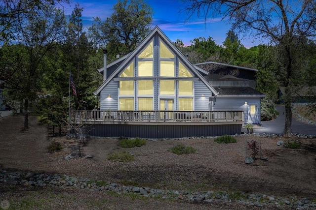 back house at dusk with a wooden deck