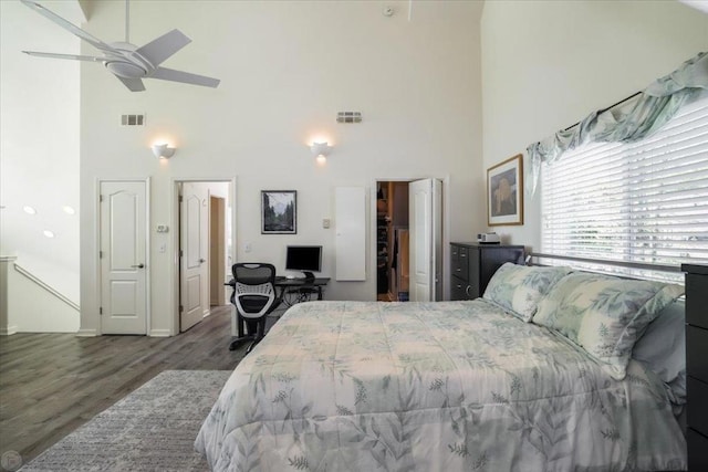 bedroom with ceiling fan, dark hardwood / wood-style floors, and a high ceiling