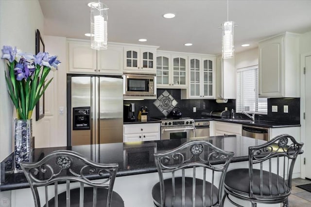 kitchen with decorative light fixtures, decorative backsplash, sink, appliances with stainless steel finishes, and white cabinets