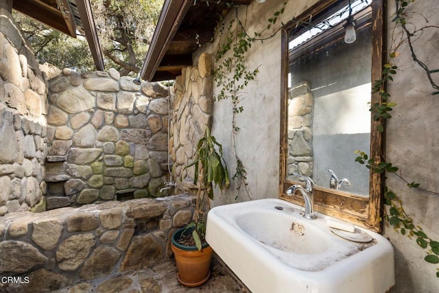 bathroom with beamed ceiling, a healthy amount of sunlight, and sink