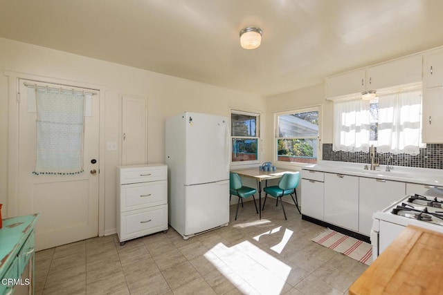 kitchen with sink, light tile patterned floors, tasteful backsplash, white appliances, and white cabinets