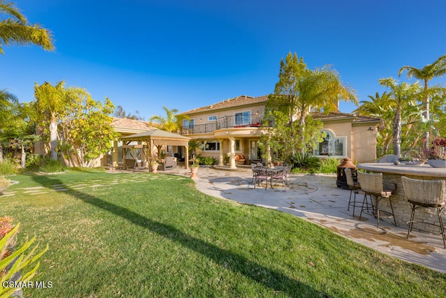 rear view of property featuring a patio, a bar, and a lawn