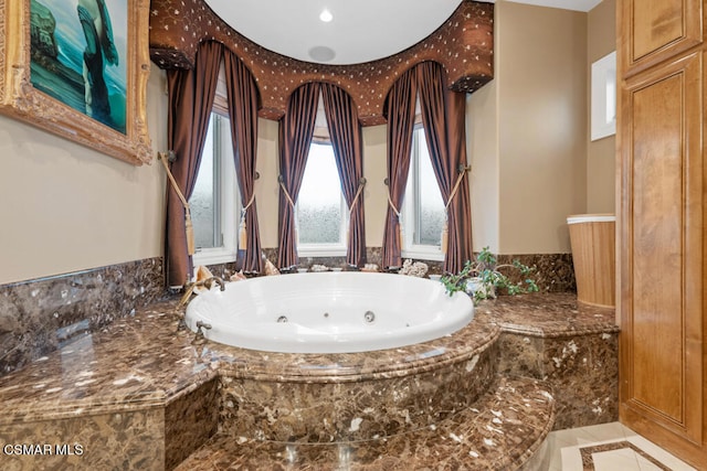 bathroom with a relaxing tiled tub and tile patterned flooring