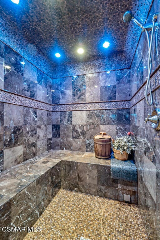 bathroom featuring tiled shower and tile walls