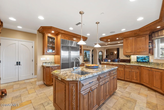 kitchen featuring pendant lighting, sink, built in refrigerator, a center island with sink, and light tile patterned floors