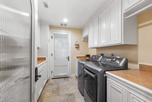 clothes washing area featuring cabinets, washer and clothes dryer, and light tile patterned floors