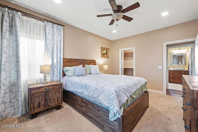 carpeted bedroom with a closet, sink, connected bathroom, a walk in closet, and ceiling fan