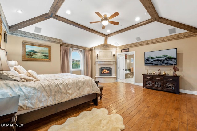 bedroom featuring ceiling fan, hardwood / wood-style flooring, connected bathroom, and vaulted ceiling