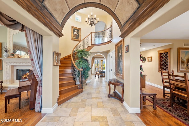 foyer with a notable chandelier, light hardwood / wood-style flooring, and a towering ceiling