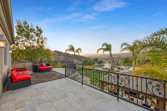 patio terrace at dusk featuring a mountain view and a balcony