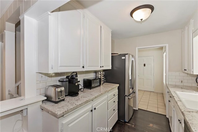 kitchen with decorative backsplash, white cabinetry, light stone counters, and dark hardwood / wood-style floors