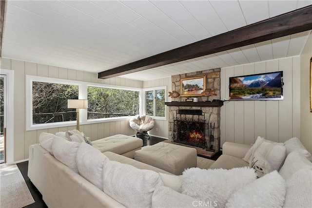 living room featuring beam ceiling, wooden walls, and a fireplace