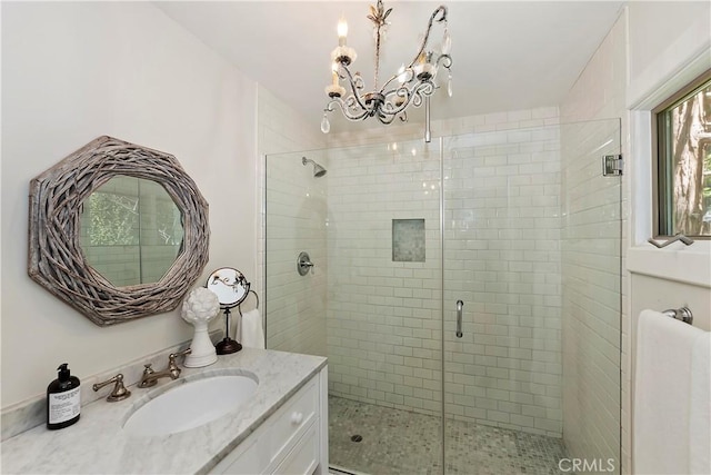 bathroom featuring a chandelier, vanity, and a shower with shower door