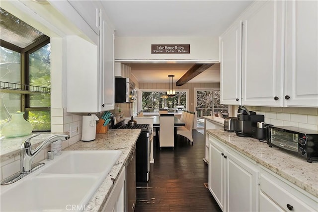 kitchen with pendant lighting, white cabinets, sink, and appliances with stainless steel finishes