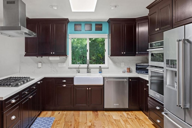 kitchen featuring wall chimney exhaust hood, decorative backsplash, sink, and appliances with stainless steel finishes