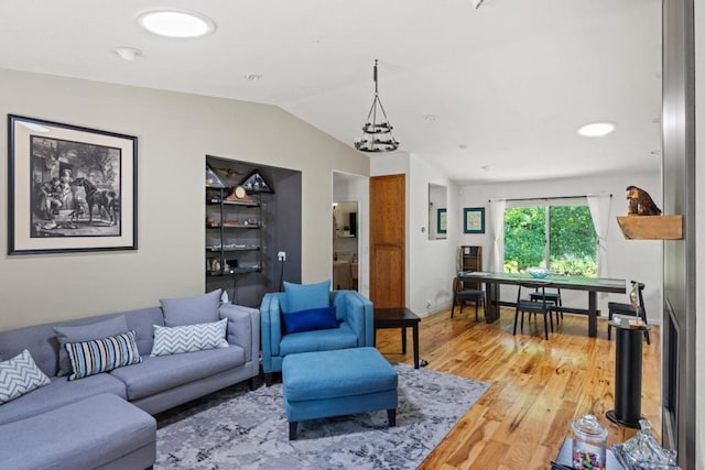 living room with wood-type flooring, lofted ceiling, and an inviting chandelier