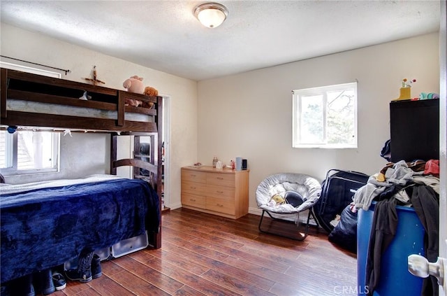 bedroom with dark hardwood / wood-style floors and multiple windows