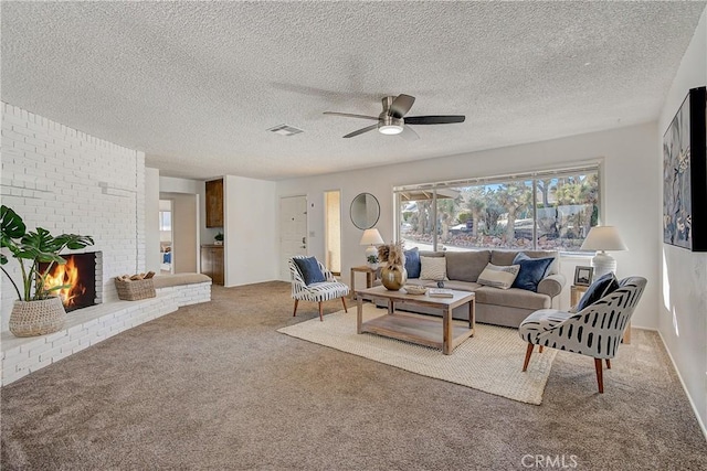 living room featuring ceiling fan, carpet, a textured ceiling, and a brick fireplace