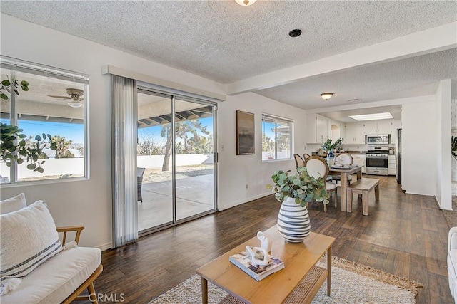 living room featuring beam ceiling, a textured ceiling, dark hardwood / wood-style floors, and ceiling fan