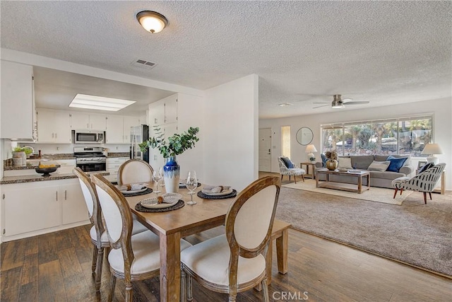 dining space featuring dark hardwood / wood-style floors, ceiling fan, and a textured ceiling