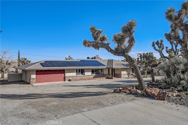 ranch-style house with solar panels and a garage